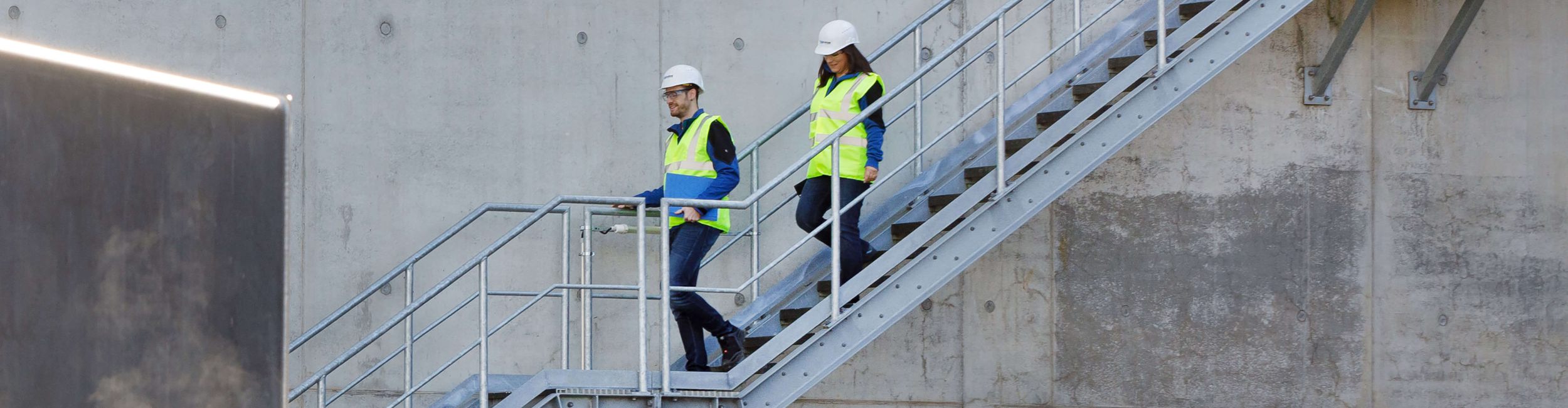 Zwei Ingenieure prüfen Konstruktionspläne vor Ort beim Kunden